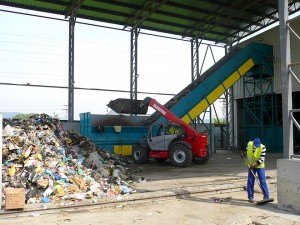 На това място отпадъците се изсипват от докаралите ги камиони, след което челен товарач ги подава към гумено-транспортна лента, която ги внася в залата за ръчно сепариране